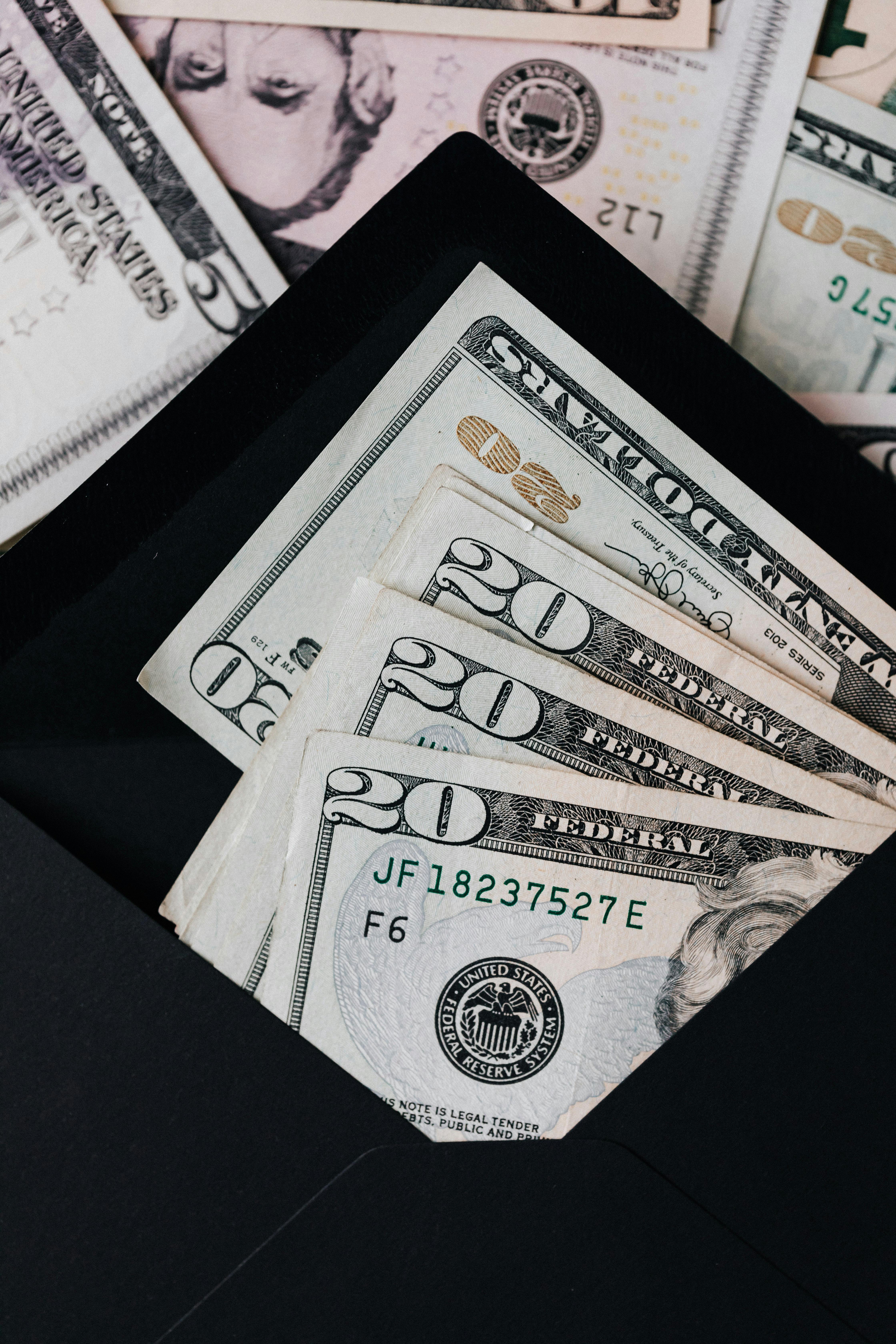 stack of dollars and black envelope with banknotes inside