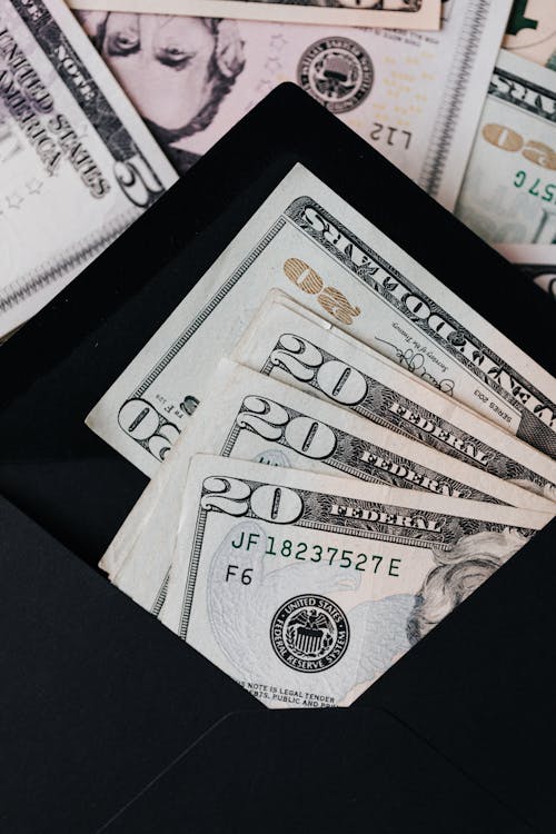 Free Stack of dollars and black envelope with banknotes inside Stock Photo