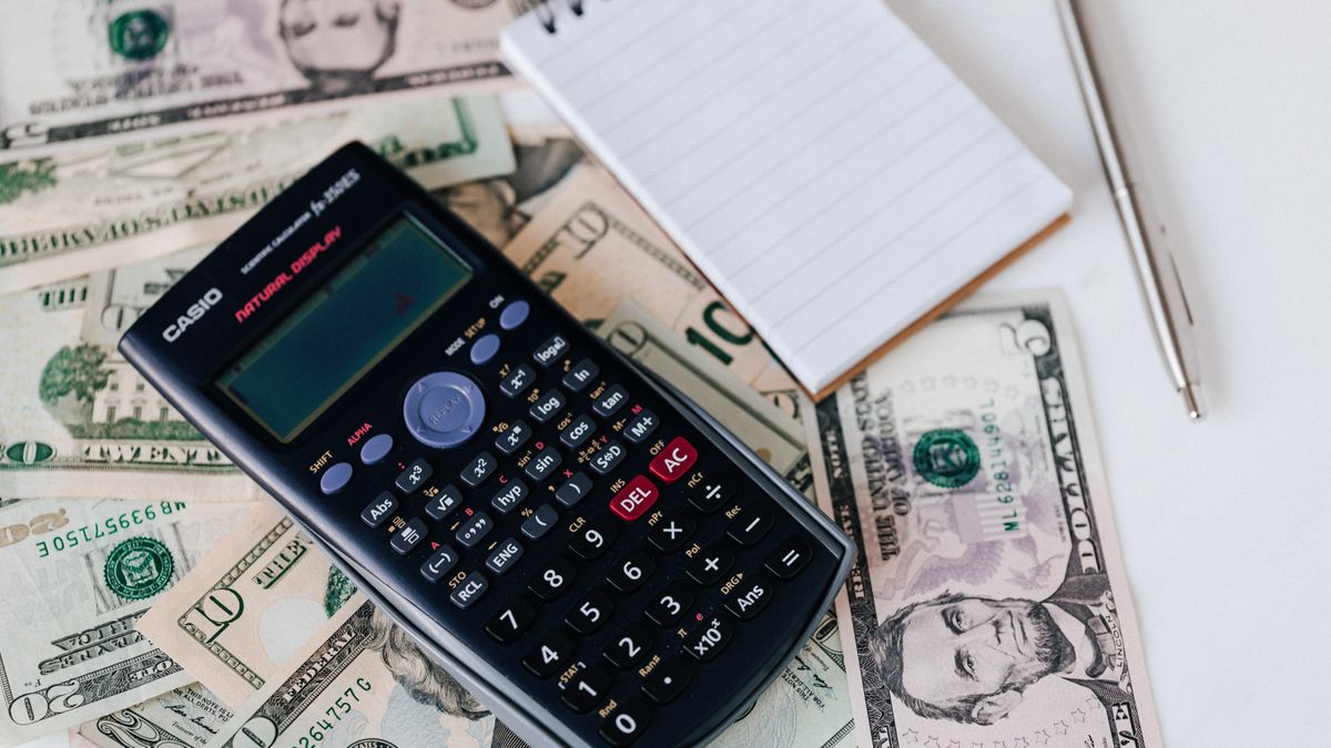 A bookkeeper working through paperwork and a calculator at a desk, the kind of manual review a VA does by hand