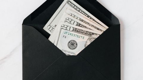 Top view of opened envelope with USA banknotes of 20 dollars placed on white marble desk illustrating concept of money gift or charity