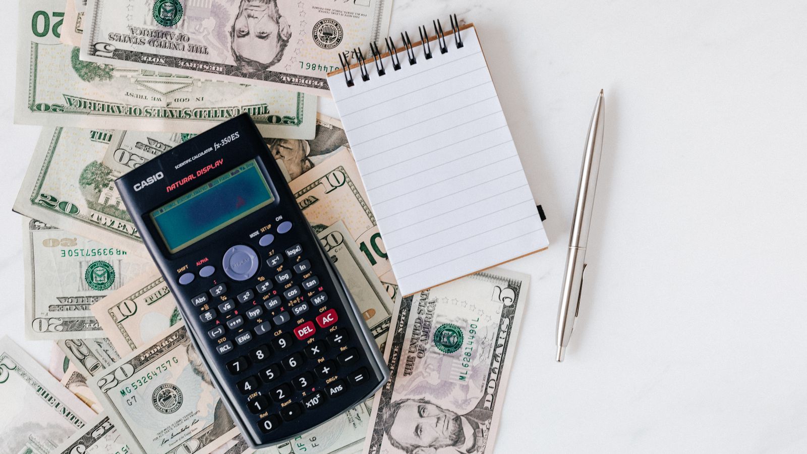 Open notebook with budget categories handwritten in three columns next to a calculator