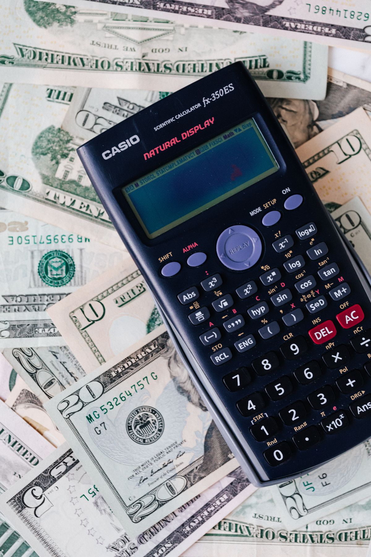 A calculator rests on a stack of US dollar bills, illustrating how token costs add up across a heavy coding month