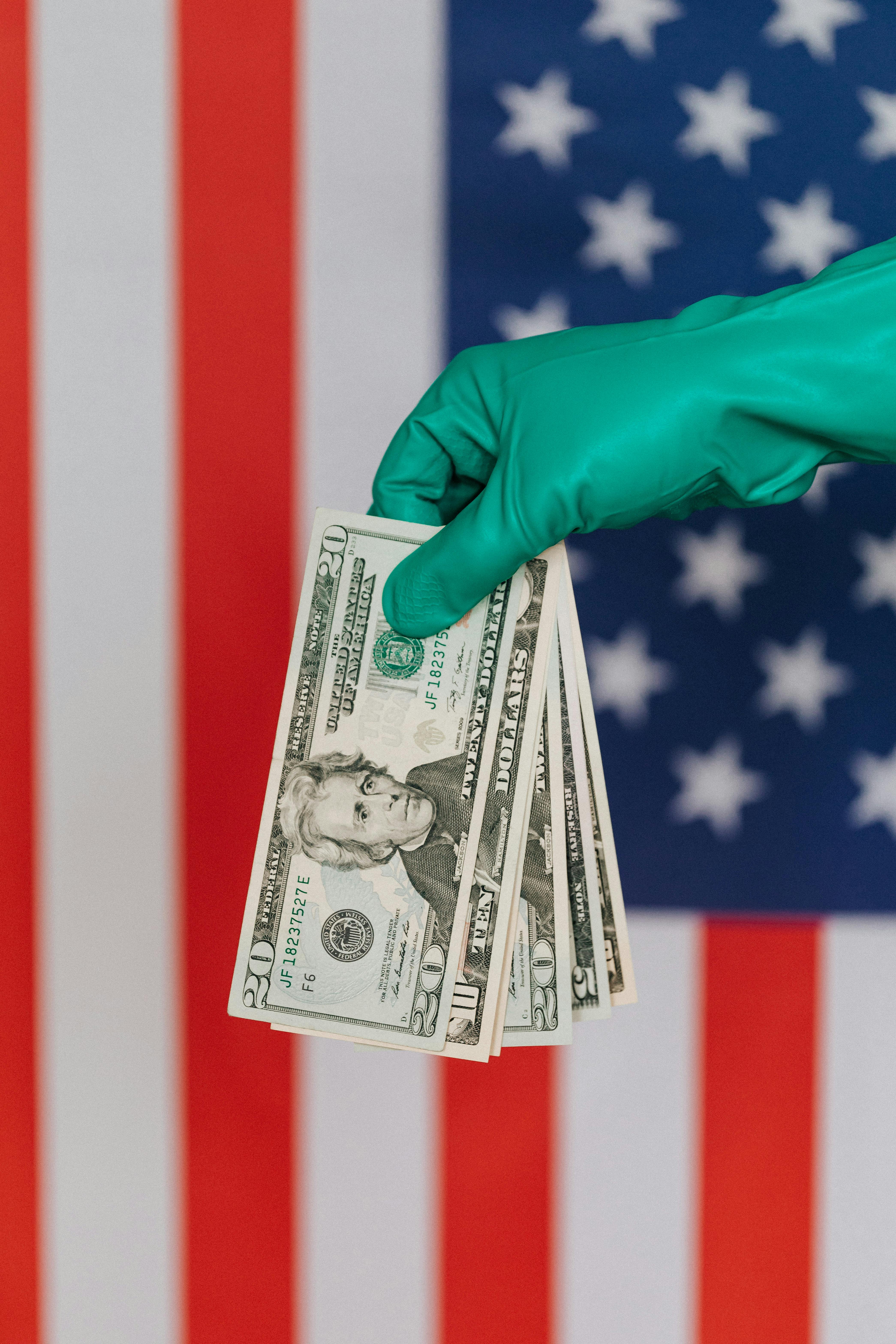 crop person in latex gloves with american money on background of flag