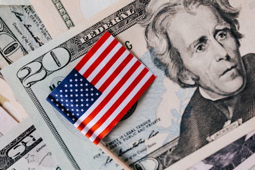 From above of small American flag placed on stack of 20 dollar bills as national currency for business financial operations