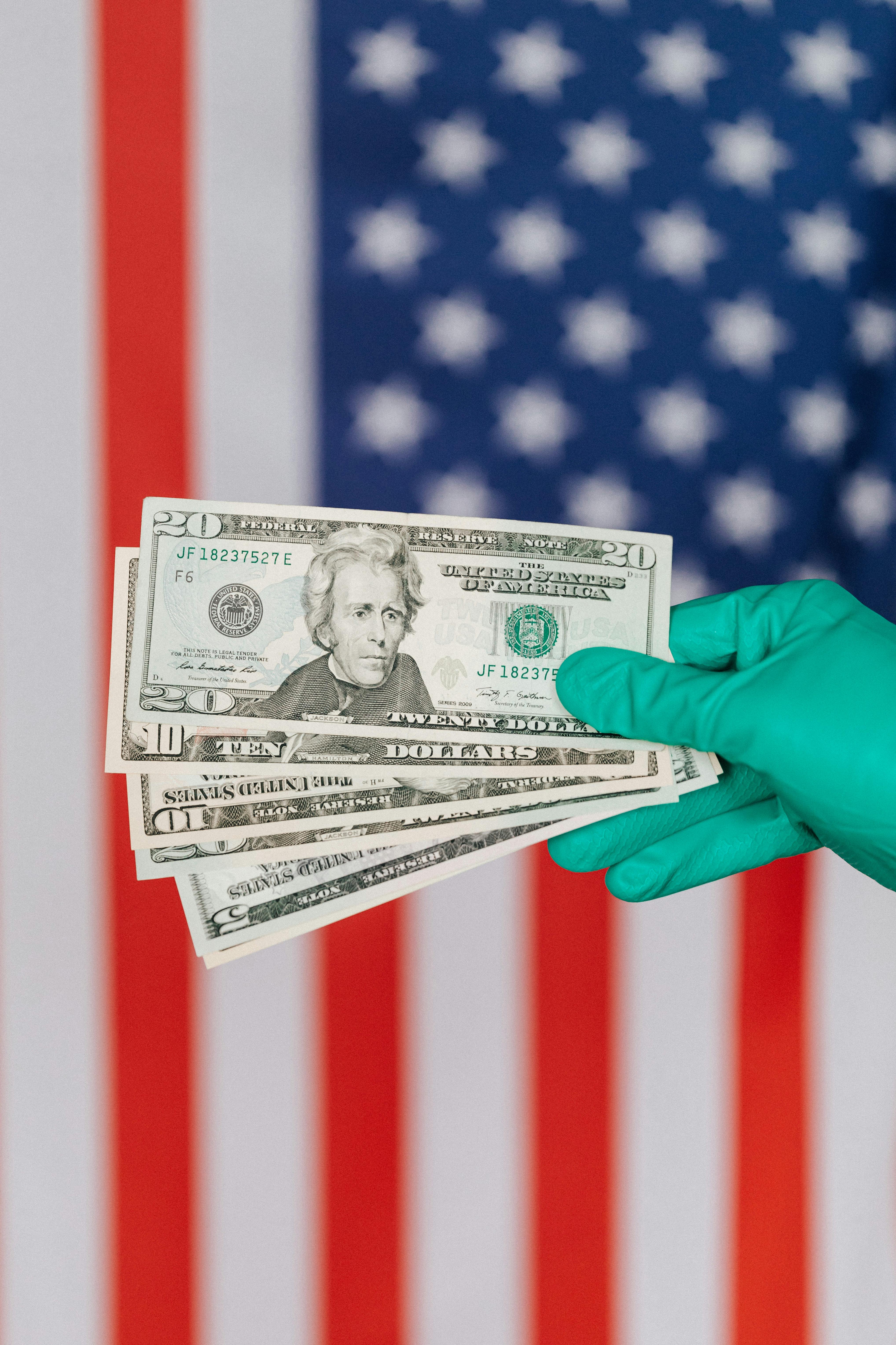 crop person showing various dollars near american flag