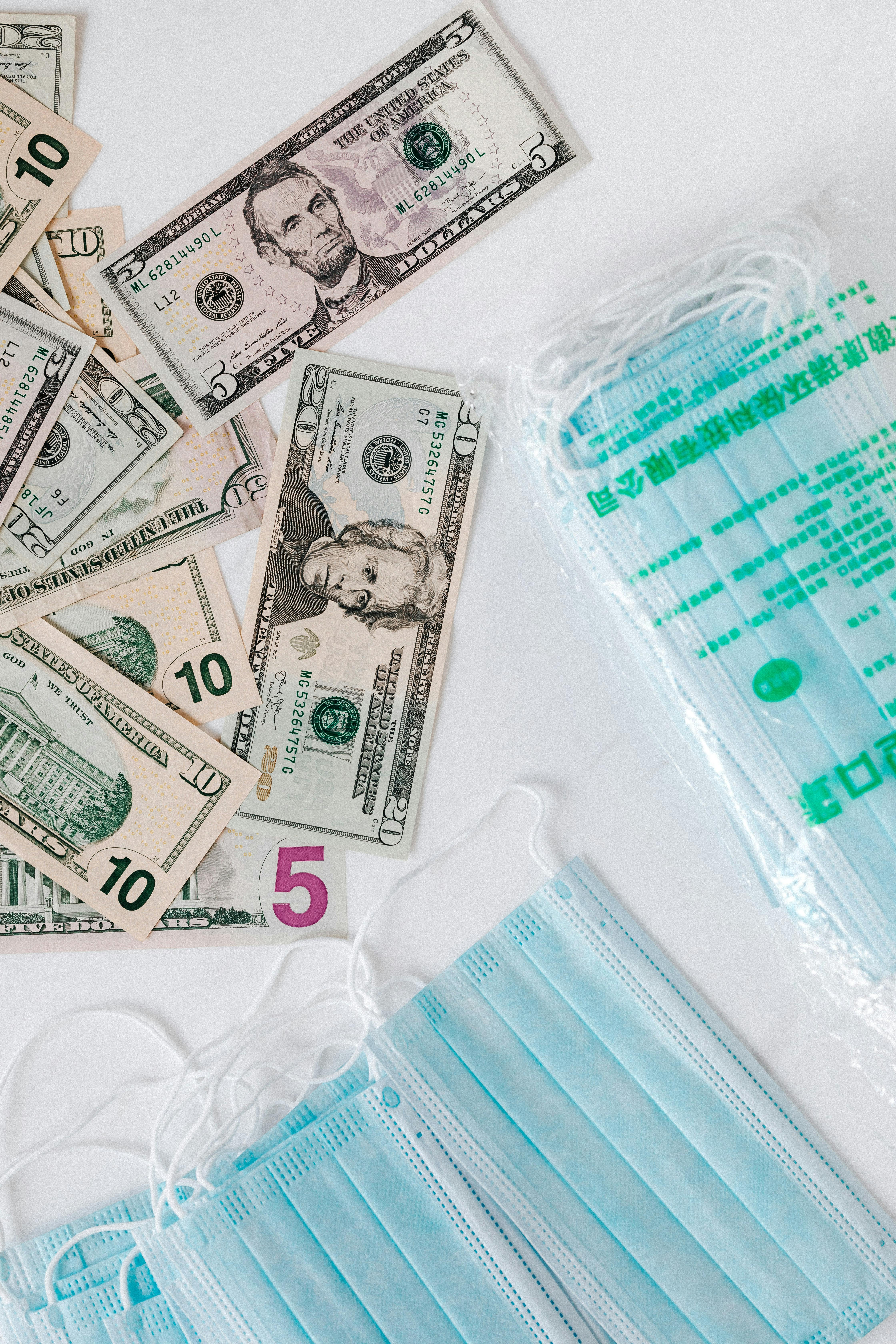 set of medical masks near diverse dollars on table