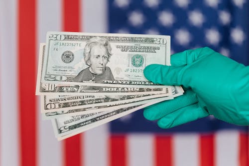 Banknotes of American dollars in hand against flag