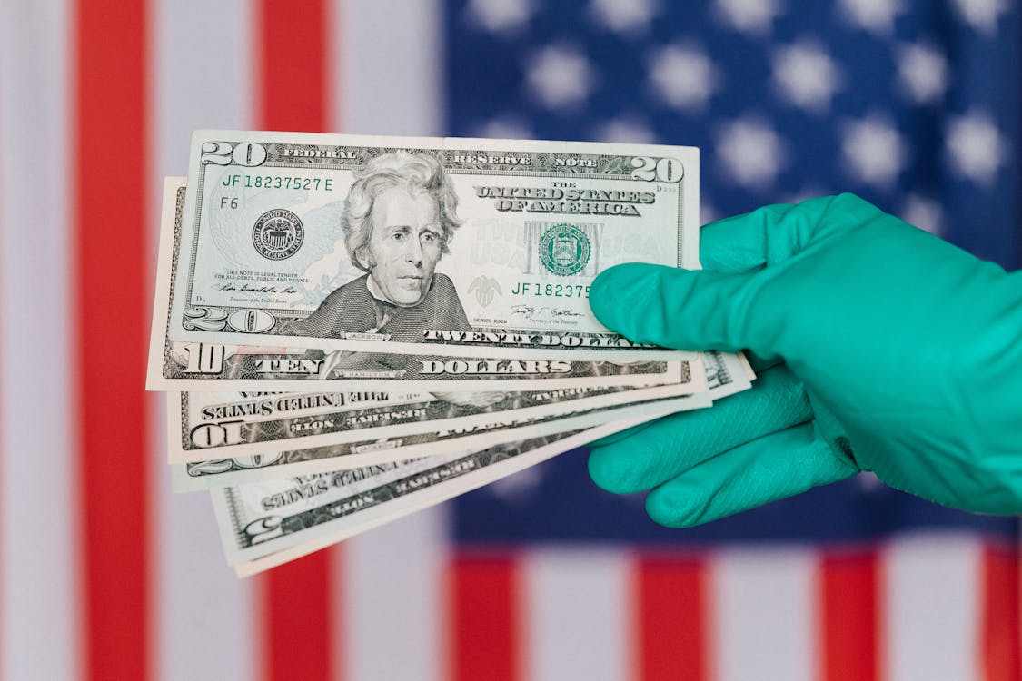 Free Banknotes of American dollars in hand against flag Stock Photo