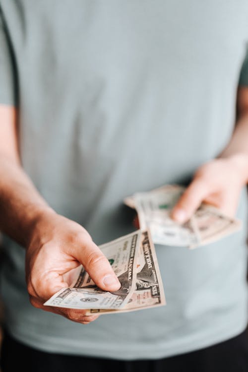 Crop man paying with American dollars