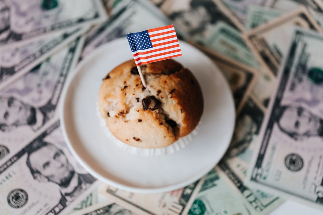 Tasty cake with flag on bunch of paper dollars