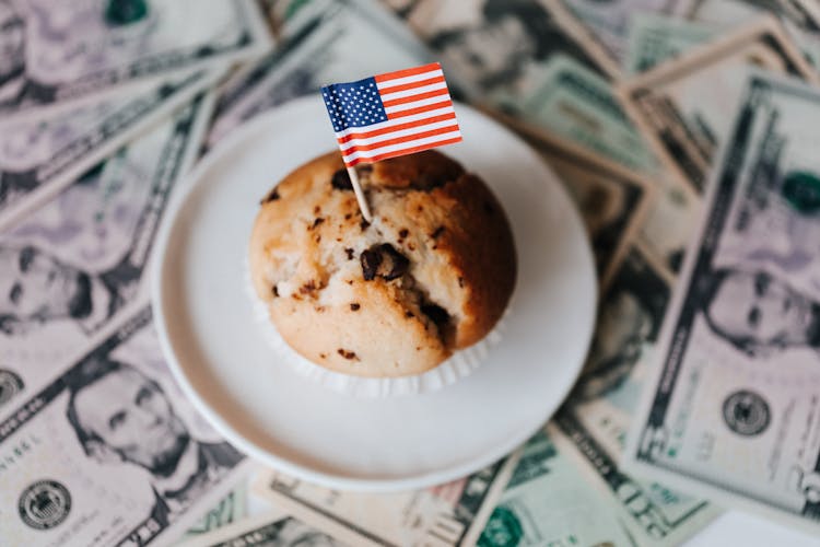 Tasty Cake With Flag On Bunch Of Paper Dollars