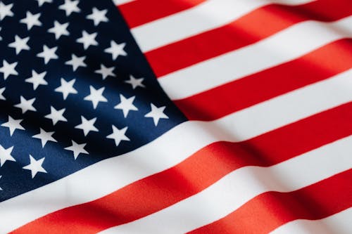 From above of closeup flattering national flag of USA with white and red stripes and stars on blue background