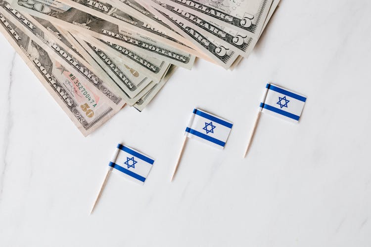 Set Of Israeli Flags On Toothpick And Heap Of Dollars