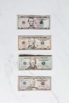 A neat flat lay of US dollar bills on a white marble surface, symbolizing finance and currency.