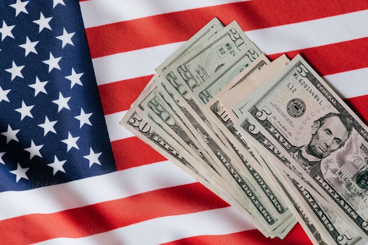 United States Flag And Pile Of Dollar Bills