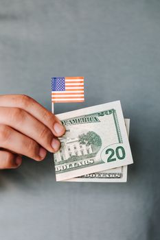 手握美国国旗和二十美元钞票，象征着美国的爱国主义和金融力量