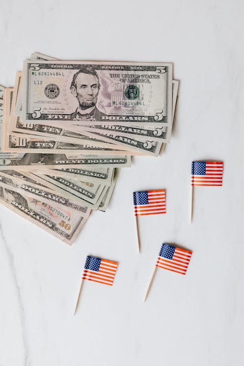 Small paper USA flags placed on white surface with dollars