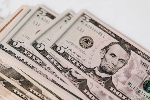 High-quality image of five dollar bills in a neat stack, representing currency and financial concepts.