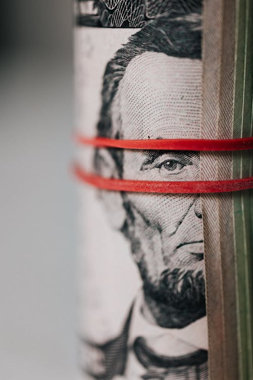 Free Closeup of rolled United States five dollar bills tightened with red rubber band Stock Photo