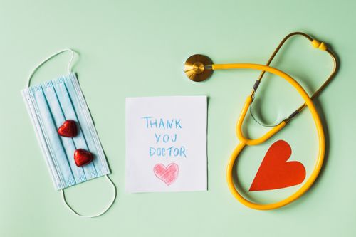 Free Flat lay of thank you note for doctors with stethoscope, mask, and hearts on green background. Stock Photo