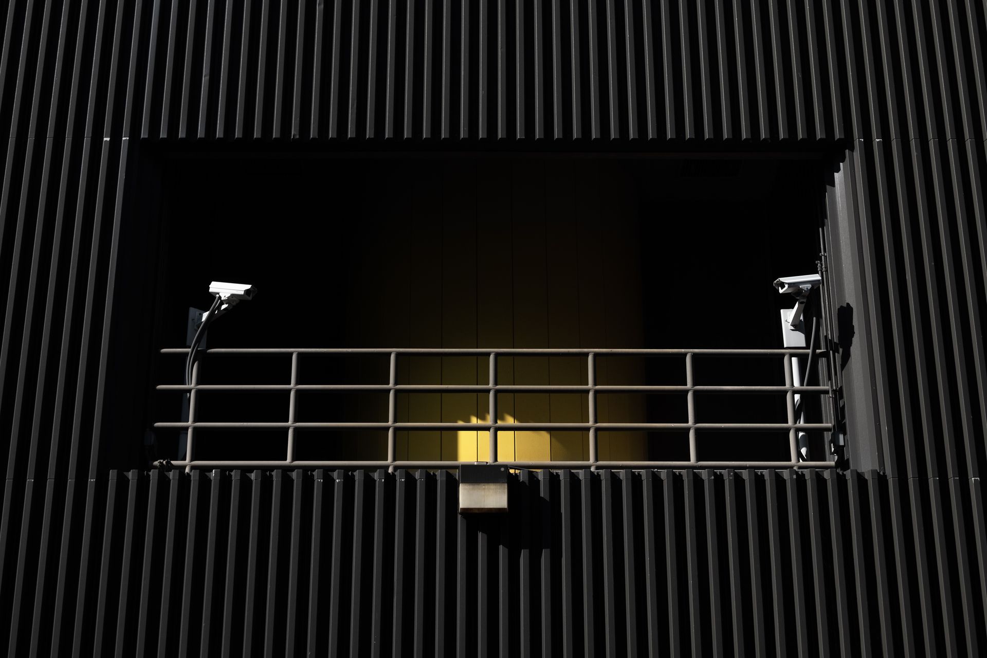 Exterior of a modern building with metal railing and security cameras in Cambridge, MA.