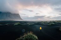 Person in Yellow Jacket Standing on Green Grass Field Near Mountain