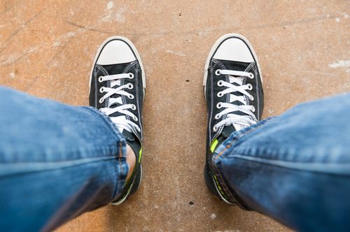 Free Pair of black sneakers with white shoelaces on a stone surface, captured from above. Stock Photo