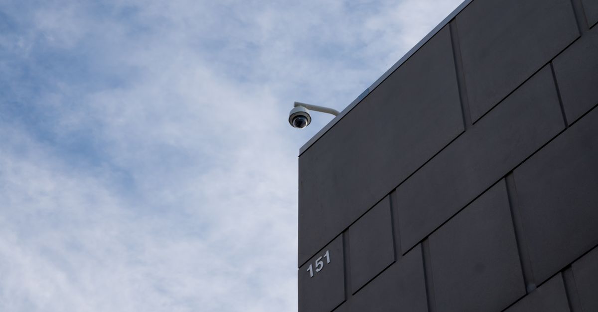 A modern building facade with a security camera against a cloudy sky in Fort Worth, TX.