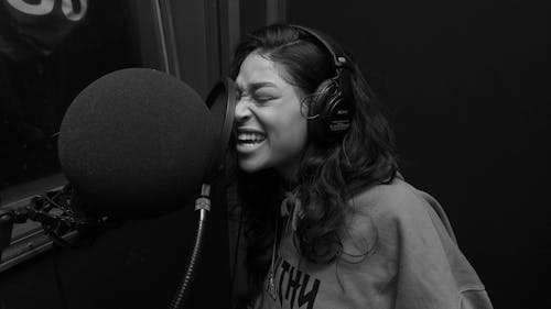 Woman in Gray Crew Neck Shirt Singing While Wearing Black Headphones