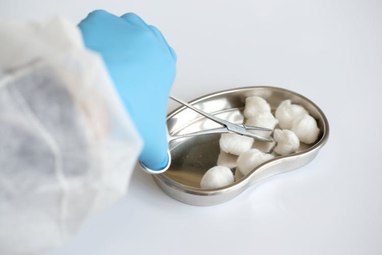 A Close-Up Shot Of A Medical Professional Using Forceps To Get A Cotton Ball