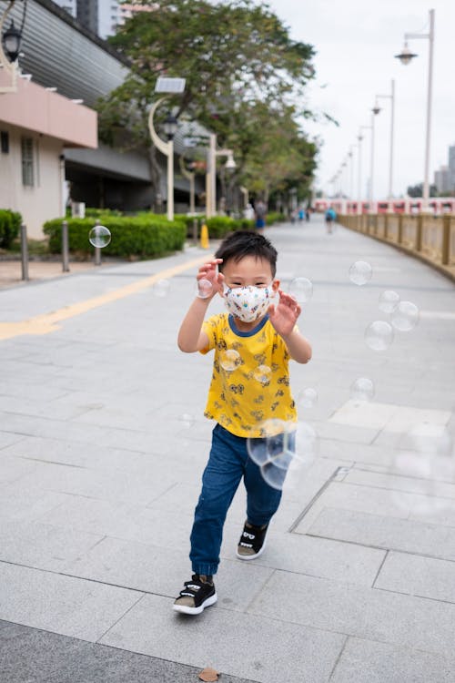 Boy in Blue and White Crew Neck T-shirt and Blue Denim Jeans Playing Bubbles during