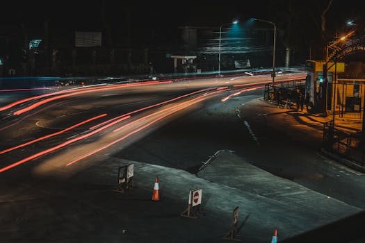 Long exposure of a city intersection at night showcasing vibrant light trails and urban infrastructure.