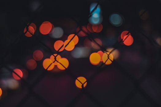 夜晚，散焦的城市灯光在轮廓围栏后营造出充满活力的光斑