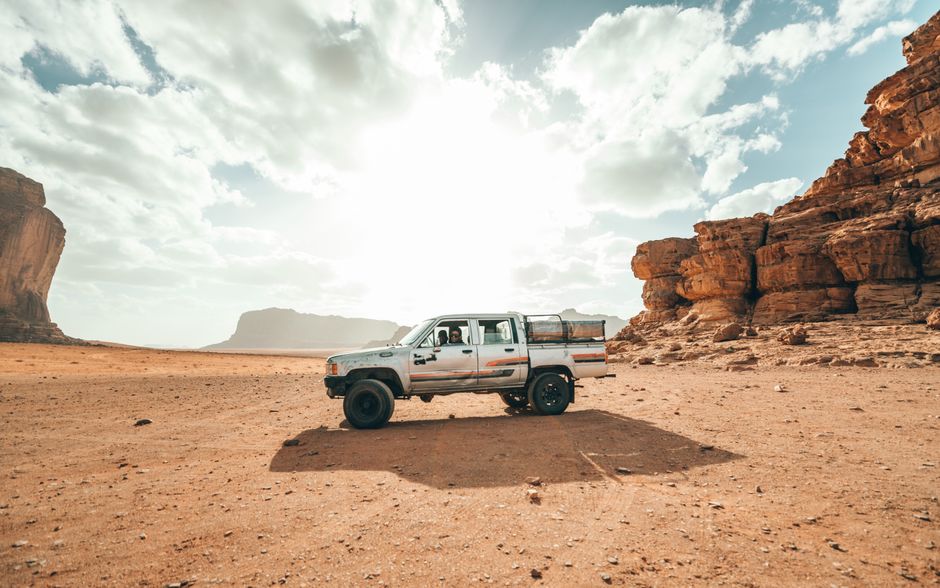 A jeep driving through the stunning red desert landscapes of Wadi Rum, Jordan