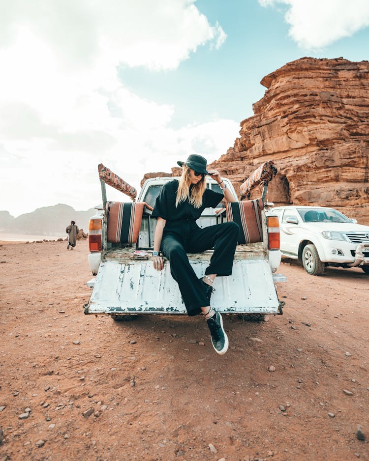 Stylish Woman Sitting On Car In Desert Area