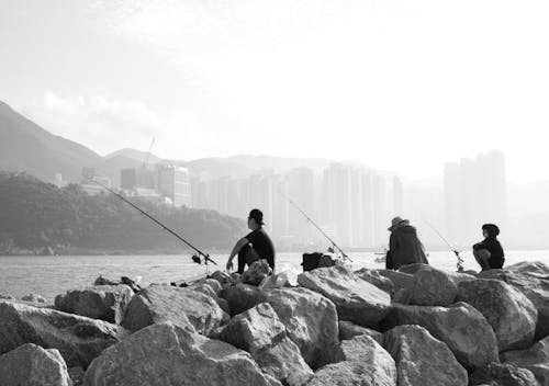 Free People with Fishing Rods on Rocks Stock Photo