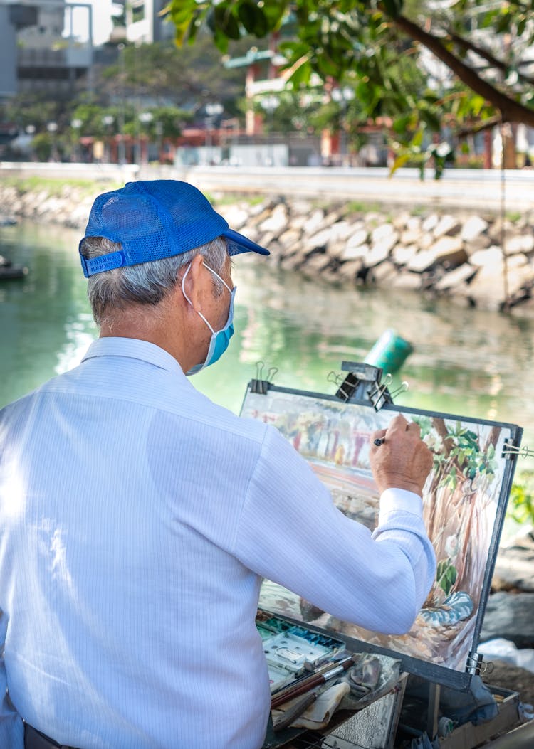 Back View Of A Man Doing Painting Near The Lake 