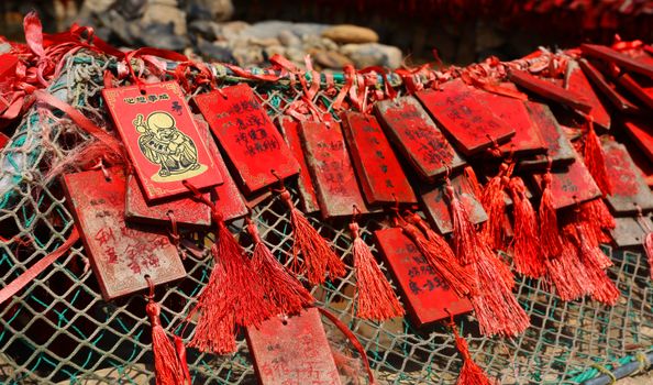 特写镜头捕捉到了悬挂在户外的红色木制护身符，展现了中国文化传统的精髓