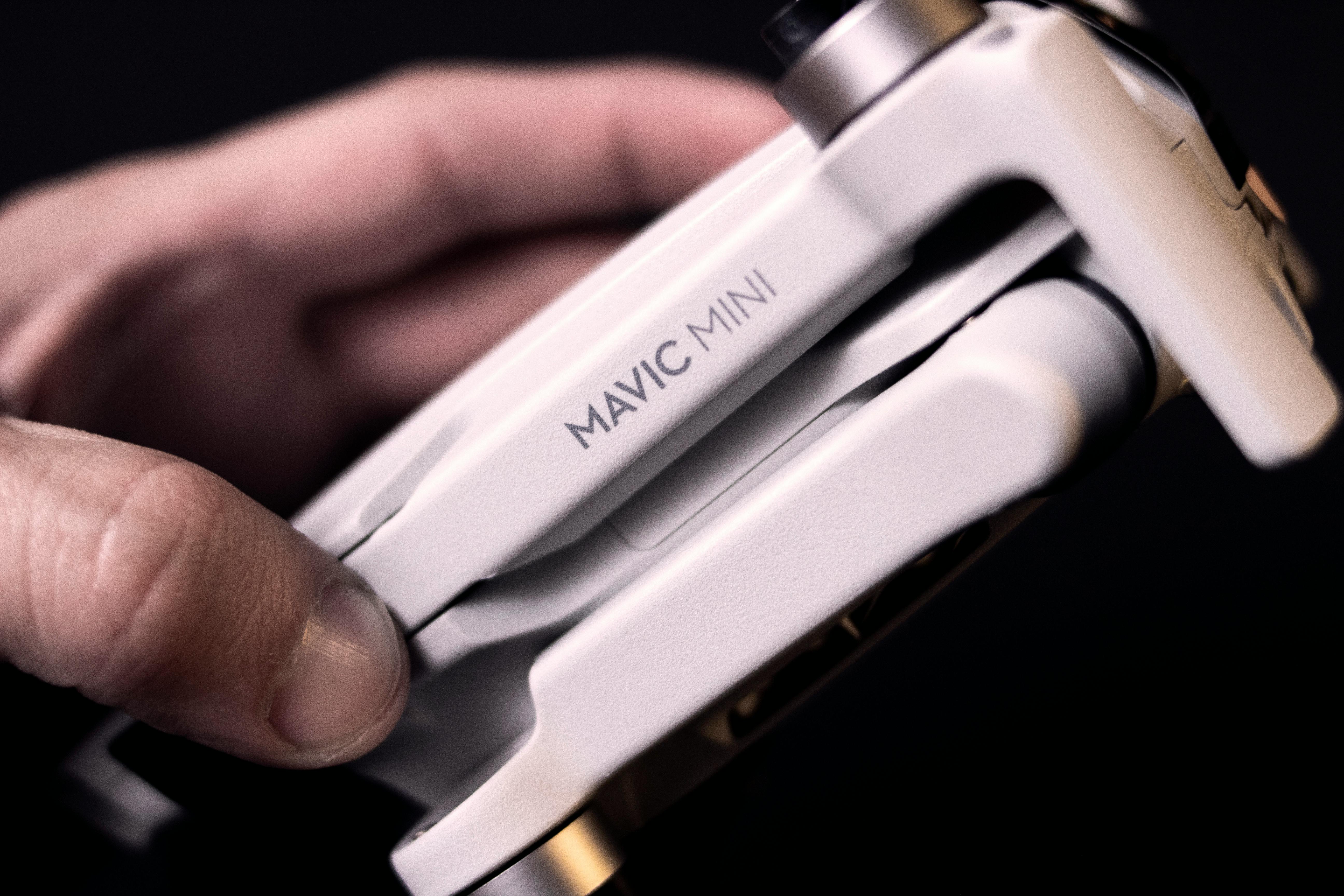 Detailed view of a Mavic Mini drone held in hand, showcasing advanced technology and compact design.