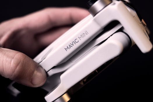 Detailed view of a Mavic Mini drone held in hand, showcasing advanced technology and compact design.