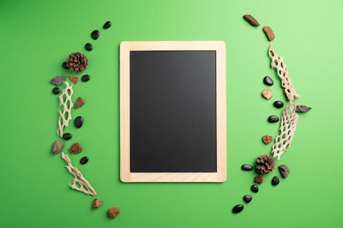 Top view of black screen of tablet with bumps and stones around on green background