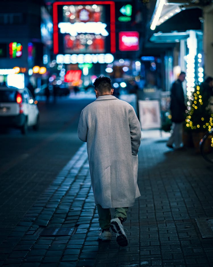 Man In Gray Coat Walking On The Street During Night Time