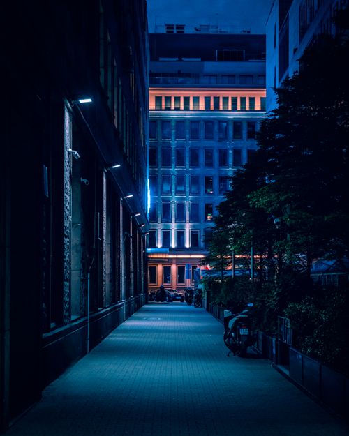 Free A nighttime view of a Warsaw alley with illuminated buildings, capturing the urban city's architectural elegance. Stock Photo