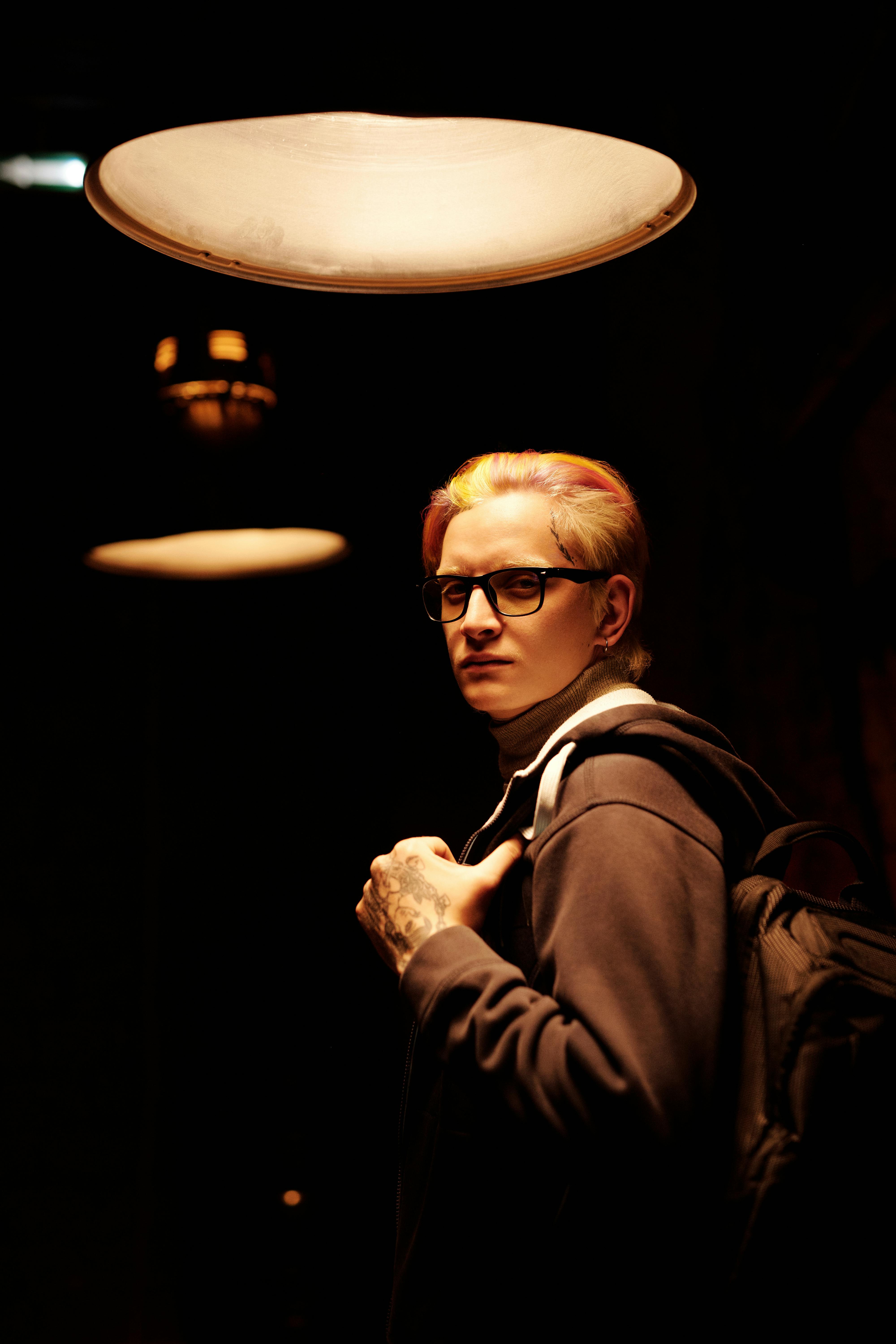 在温暖的灯光下，背着背包的年轻人肖像传达出严肃的心情