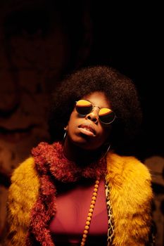 Confident woman with afro hair and sunglasses in a fashionable outfit.