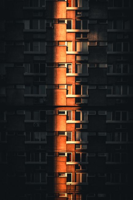 A striking view of a Warsaw apartment building with golden hour sunlight creating a dramatic effect.