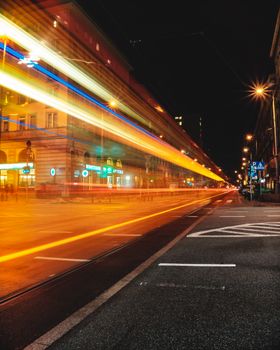 Colorful light trails illuminate the Warsaw city street at night, showcasing dynamic urban life.