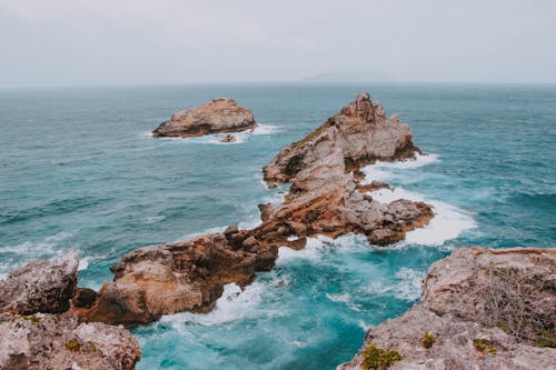 Bristly rocky formations in stormy ocean on foggy day