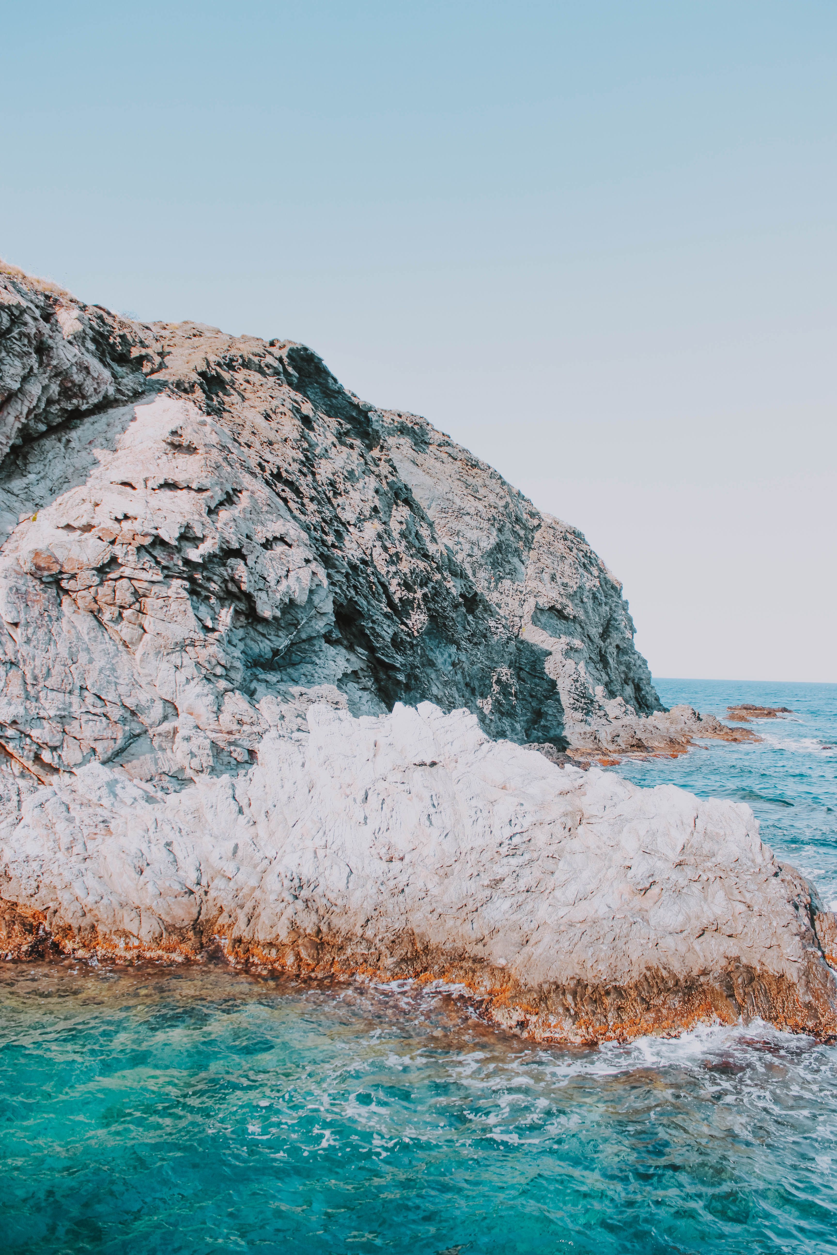 From above picturesque view of bristly mount near transparent sea water under serene sky with horizon line