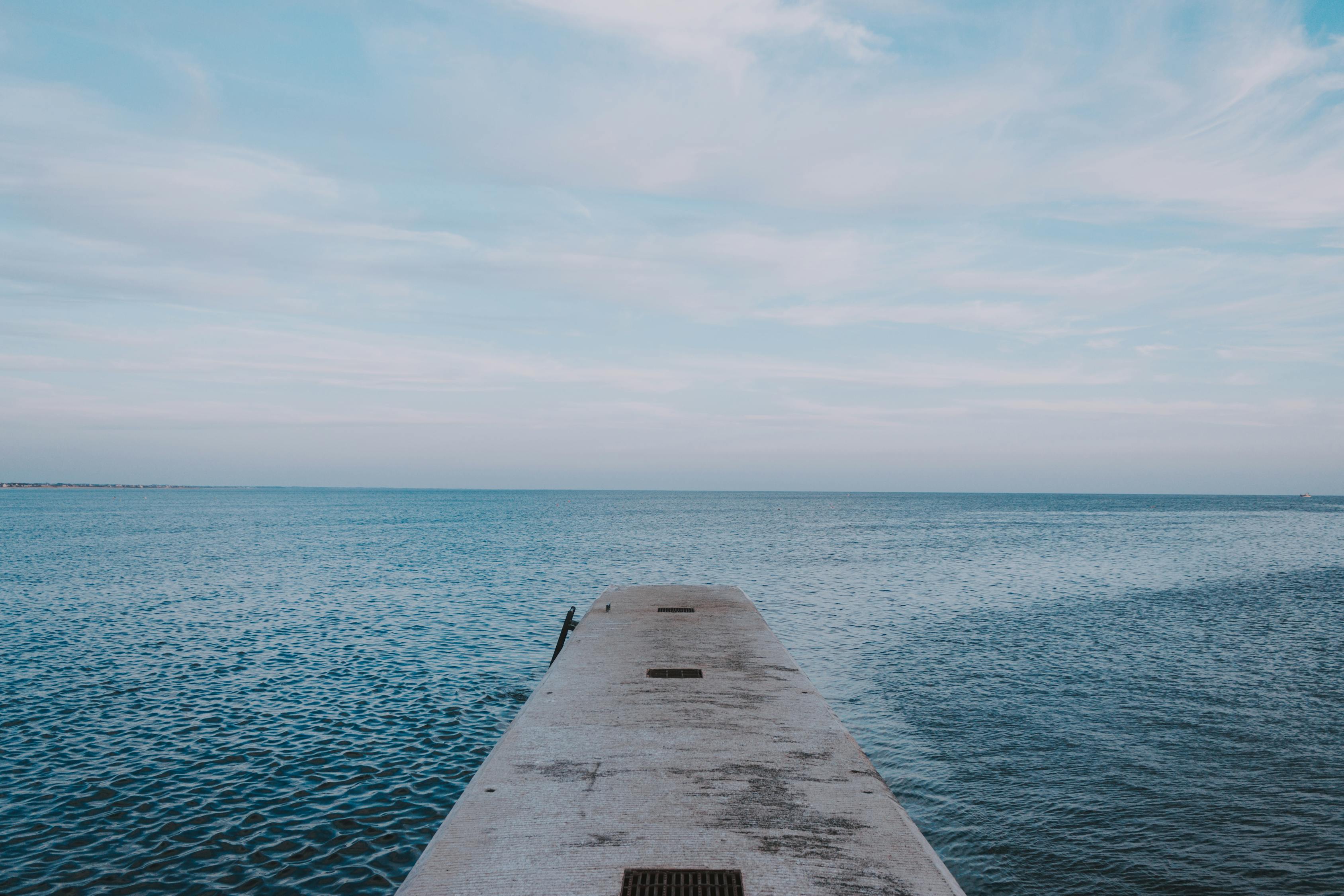Concrete pier in rippled ocean with horizon line under sky · Free Stock ...